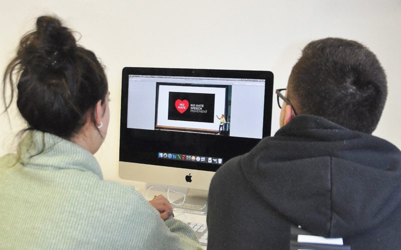Dois jovens olham para o ecrã de um computador, onde está aberto o site do "No Hate Speech Movement".