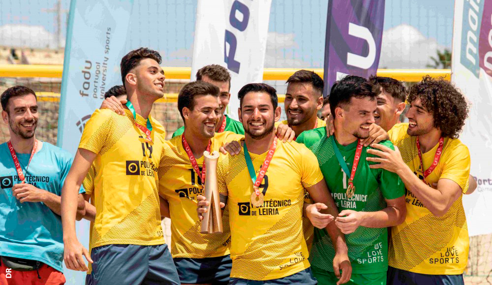 Equipa de futebol de praia do Politécnico de Leiria celebra a conquista do campeonato nacional universitário da modalidade. Ao centro, um dos jogadores segura a taça.
