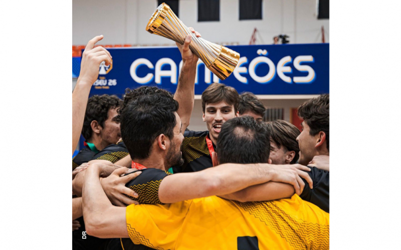 Equipa masculina de futsal do Instituto Politécnico de Leiria festeja a conquista do título de campeão nacional. O grupo de jovens está abraçado. Um deles, ao centro, ergue na mão a taça, doirada. Atrás, numa faixa a azul, lê-se, em letras brancas: "Campeões".
